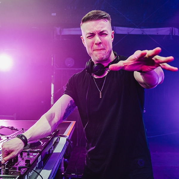 Tiscore performing as a DJ, reaching out to the crowd with an intense stage presence.